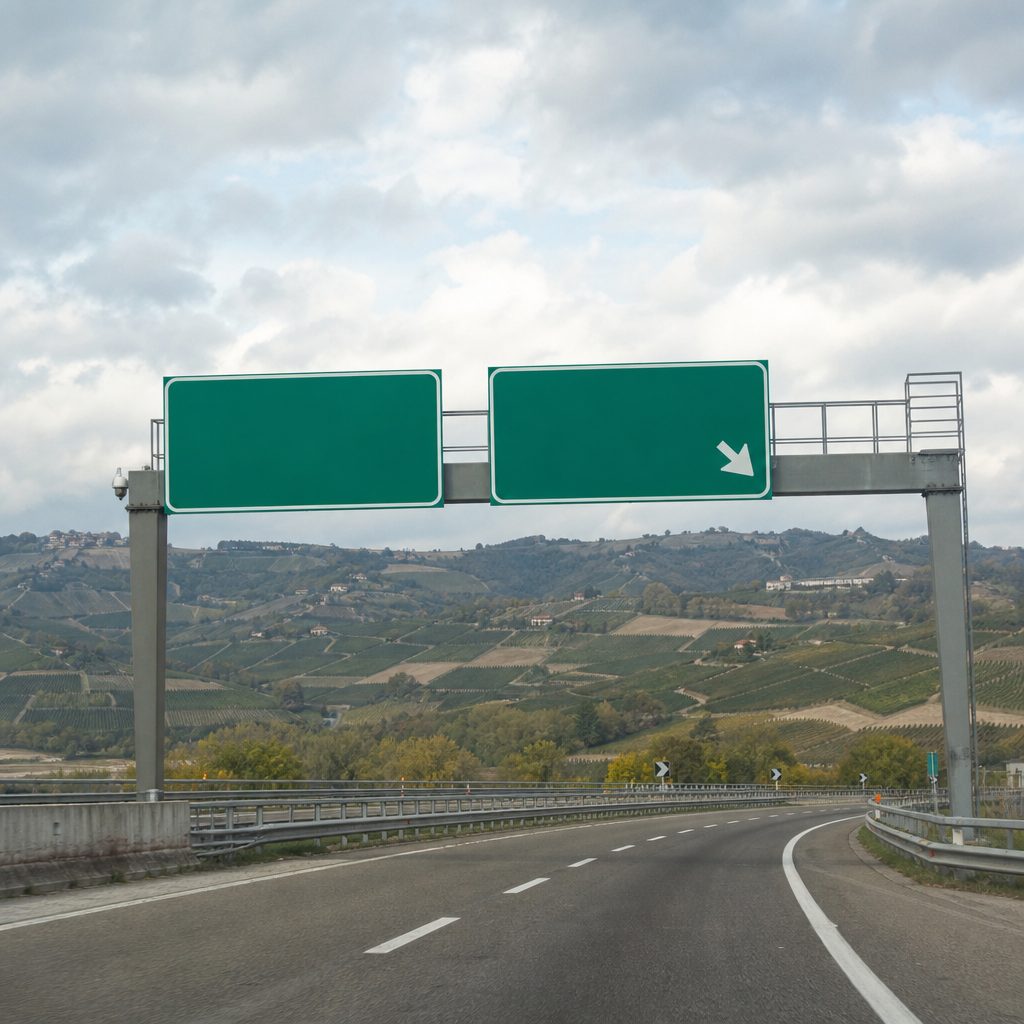 Portale autostradale con cartelli di uscita su uno sfondo di colline, luce piatta