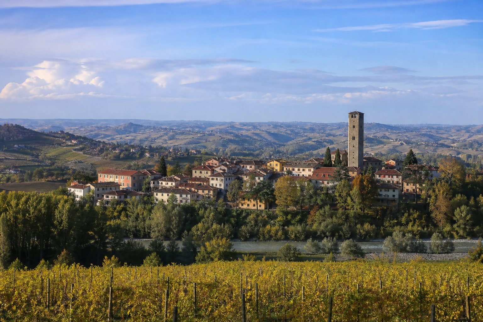 Torre in pietra che domina un piccolo borgo di vigneti su una collina bassa, con la valle del fiume sullo sfondo
