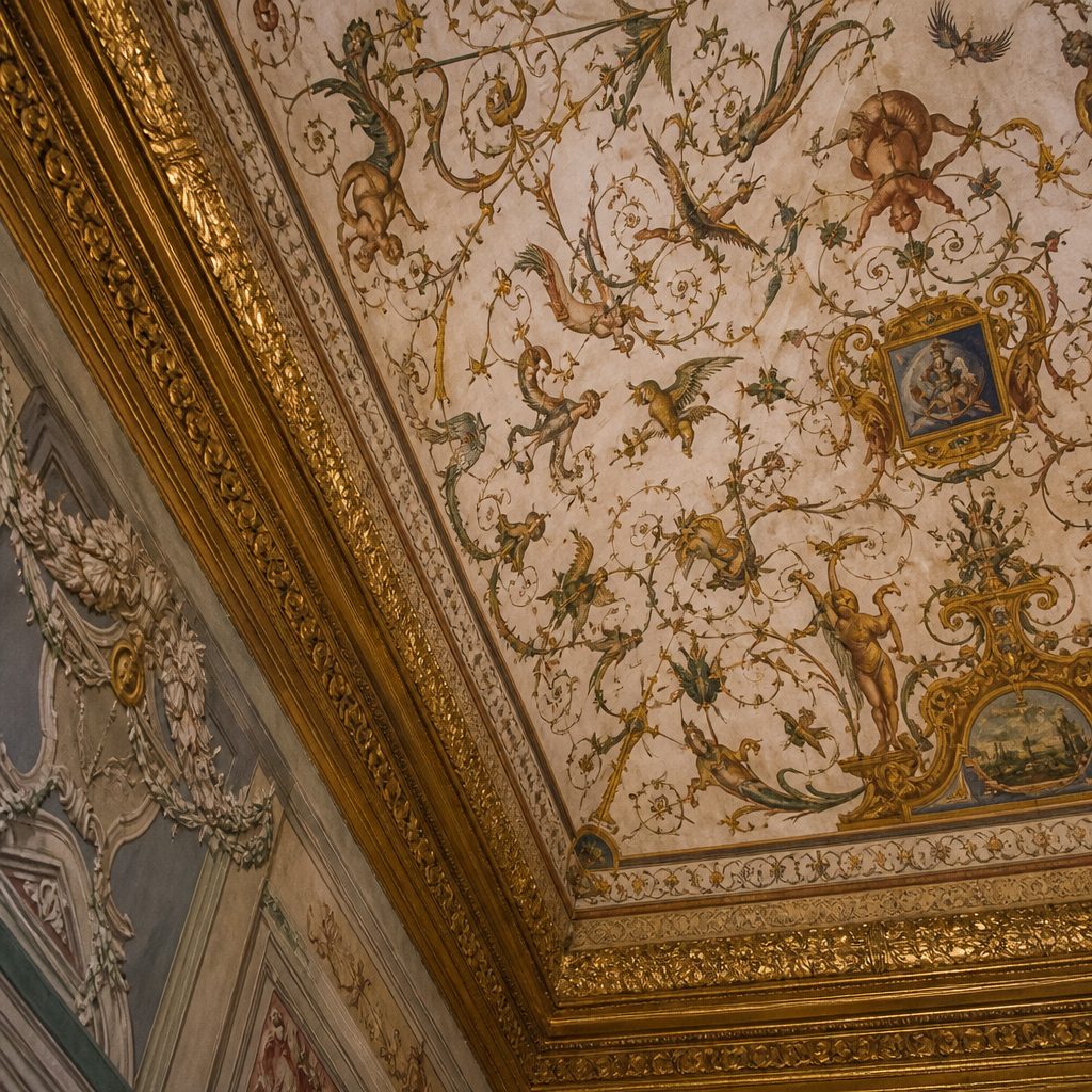 Soffitto affrescato con decorazioni a grottesche barocche e cornice dorata, ripreso dal basso