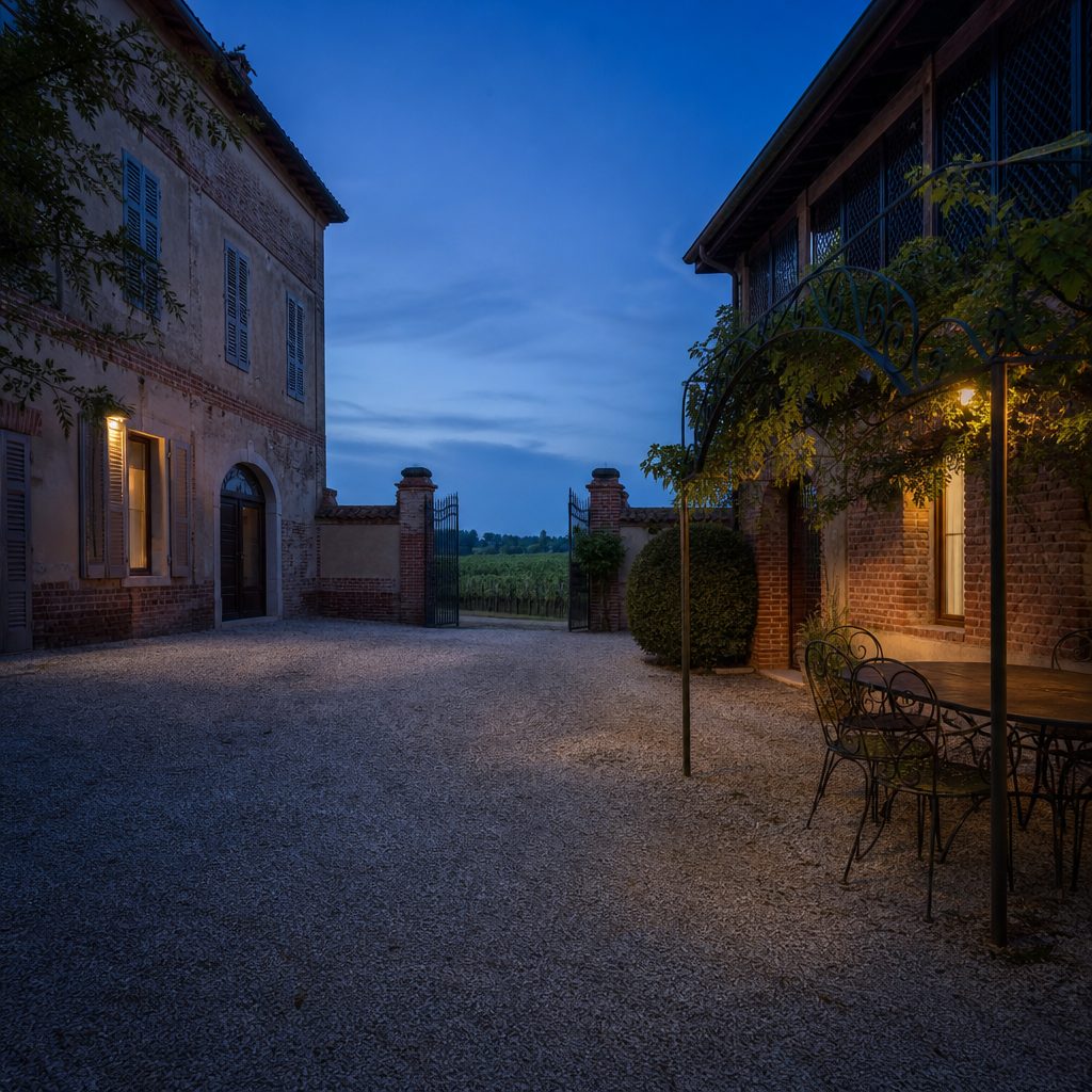 Cortile di una cascina piemontese restaurata all'ora blu, con muri in mattoni, pergolato e finestra illuminata