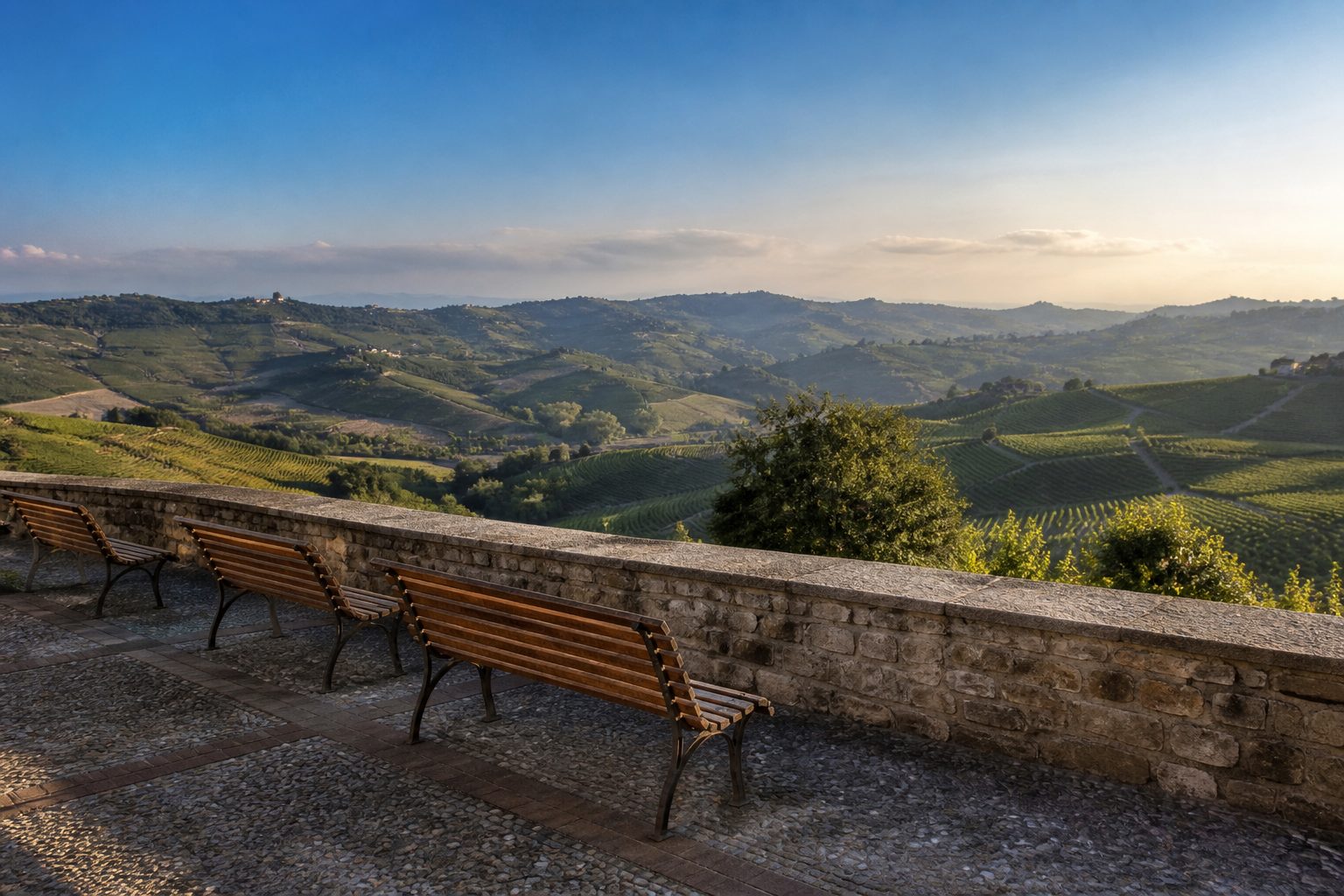 Ampia terrazza panoramica con parapetto in pietra affacciata su un mare di colline coltivate a vigneto